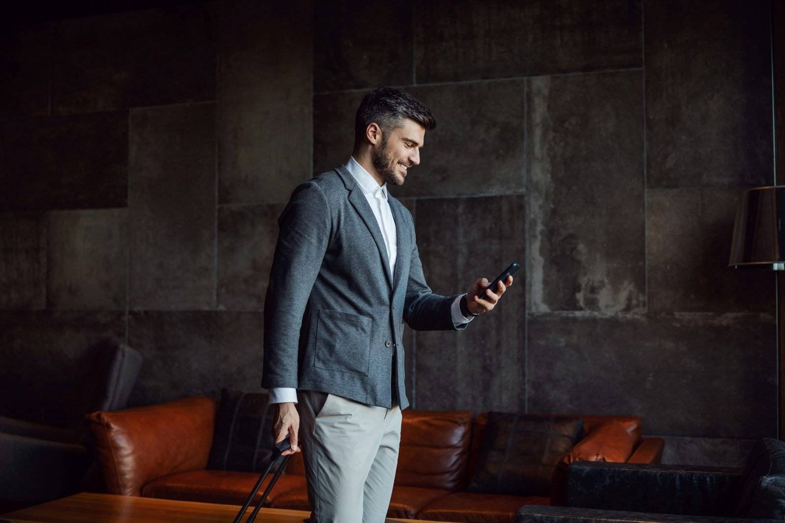 A modern AI technology executive walking with his suitcase, looking at his phone - indicating he is happy working with a specialist AI recruitment agency