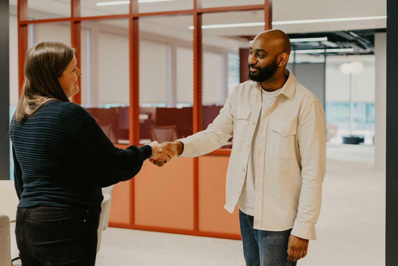 A white woman shaking a black mans hand after a successful job interview for an AI job